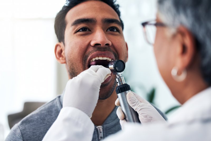 A dentist checking a patient for signs of oral cancer